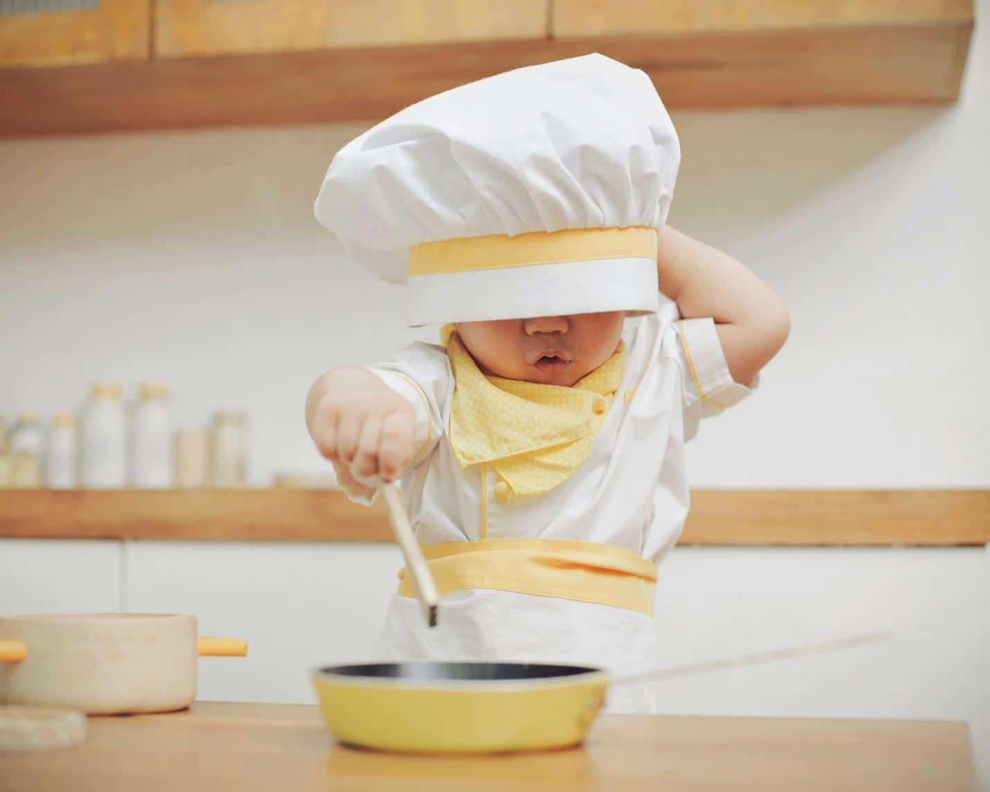 A child in a chef's hat cooking Description automatically generated