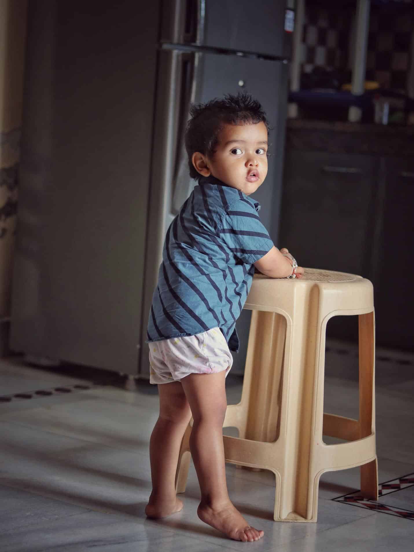 A child standing on a stool Description automatically generated