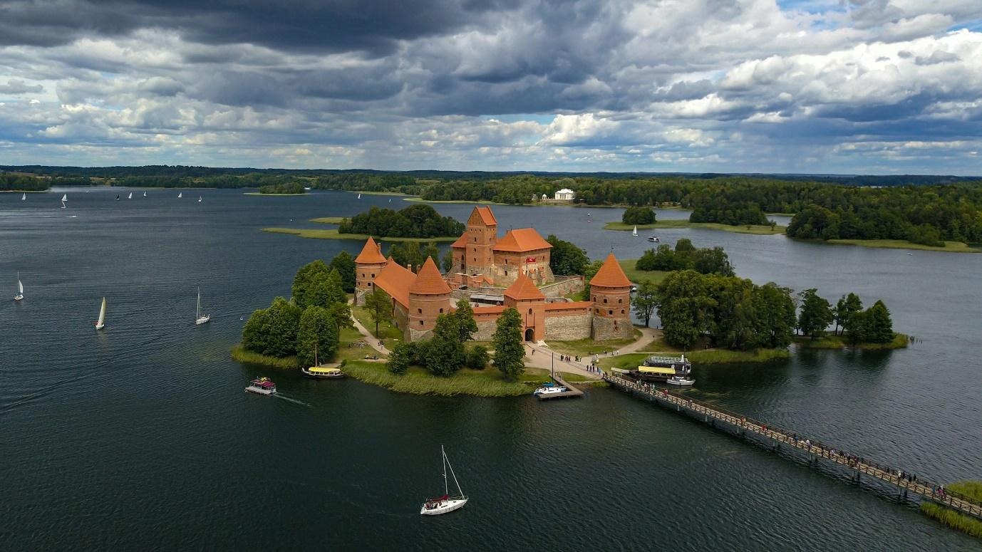 brown and orange castle on islet connected by bridge