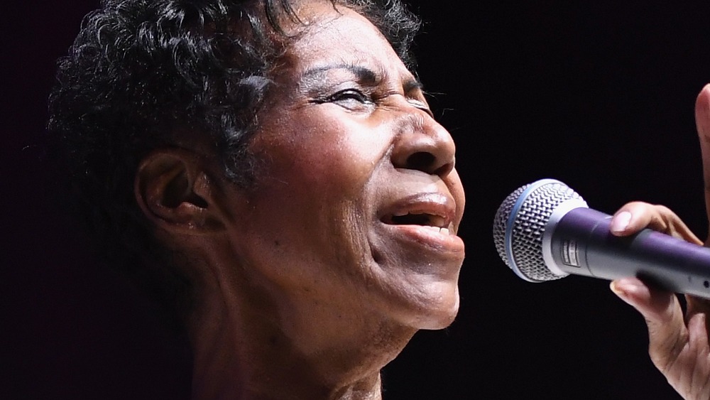 Aretha Franklin performing live on stage singing into microphone