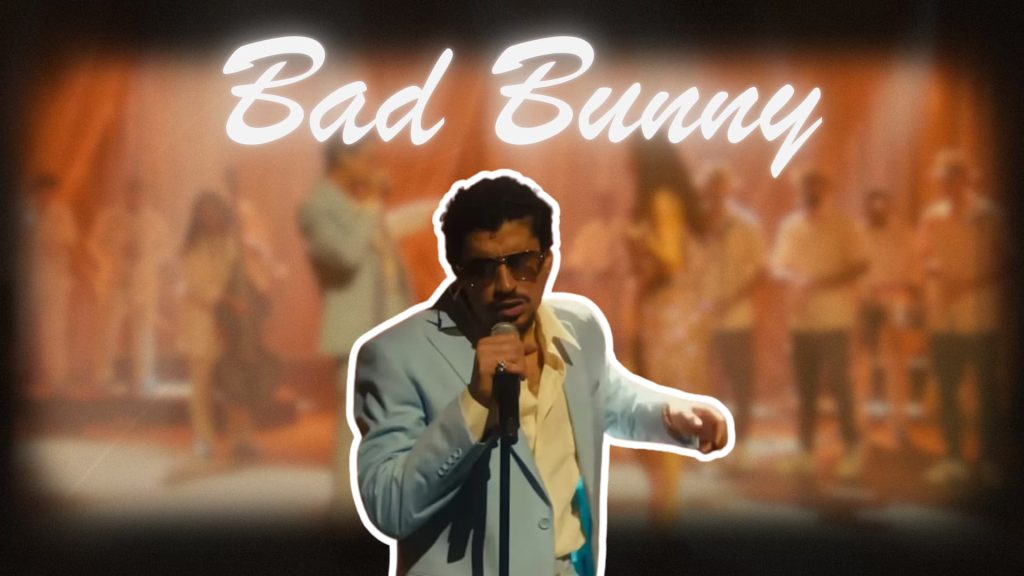 Bad Bunny performing live on stage with warm lighting and blurred band background