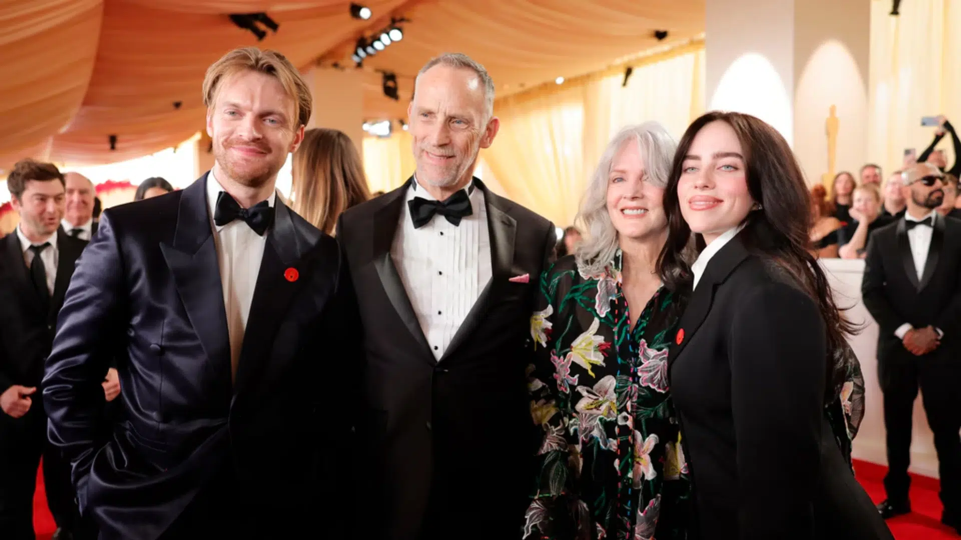 Finneas O'Connell, Patrick O'Connell, Maggie Baird, and Billie Eilish pose together on a red carpet