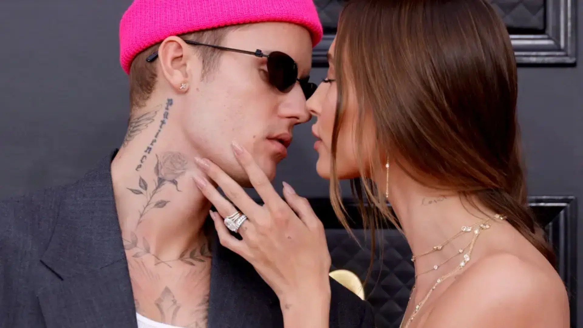 Hailey Bieber wearing oval diamond engagement ring while leaning close to Justin Bieber at event