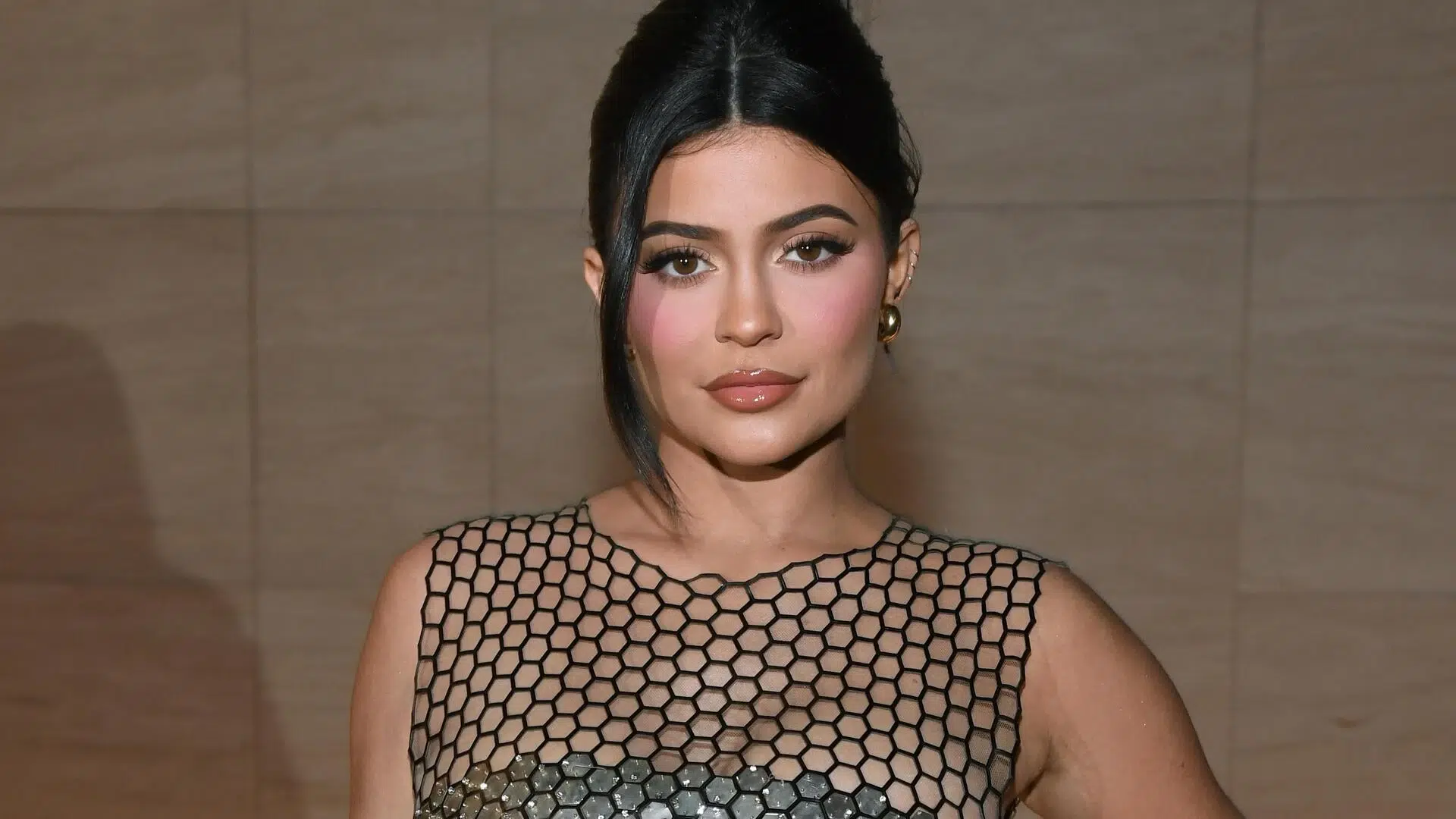 Kylie Jenner in a black gown with hair in a bun at an event.