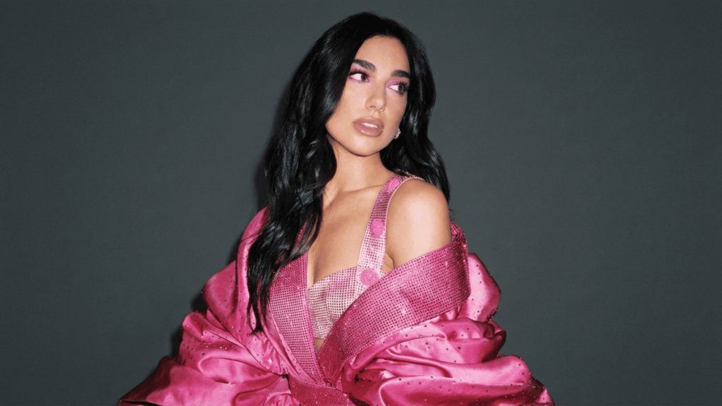 dua lipa wearing a pink sequined outfit and bold pink eye makeup against a dark gray background