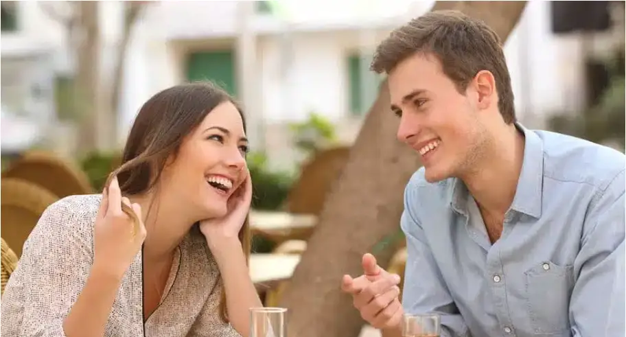 Two people conversing and laughing at an outdoor cafe table