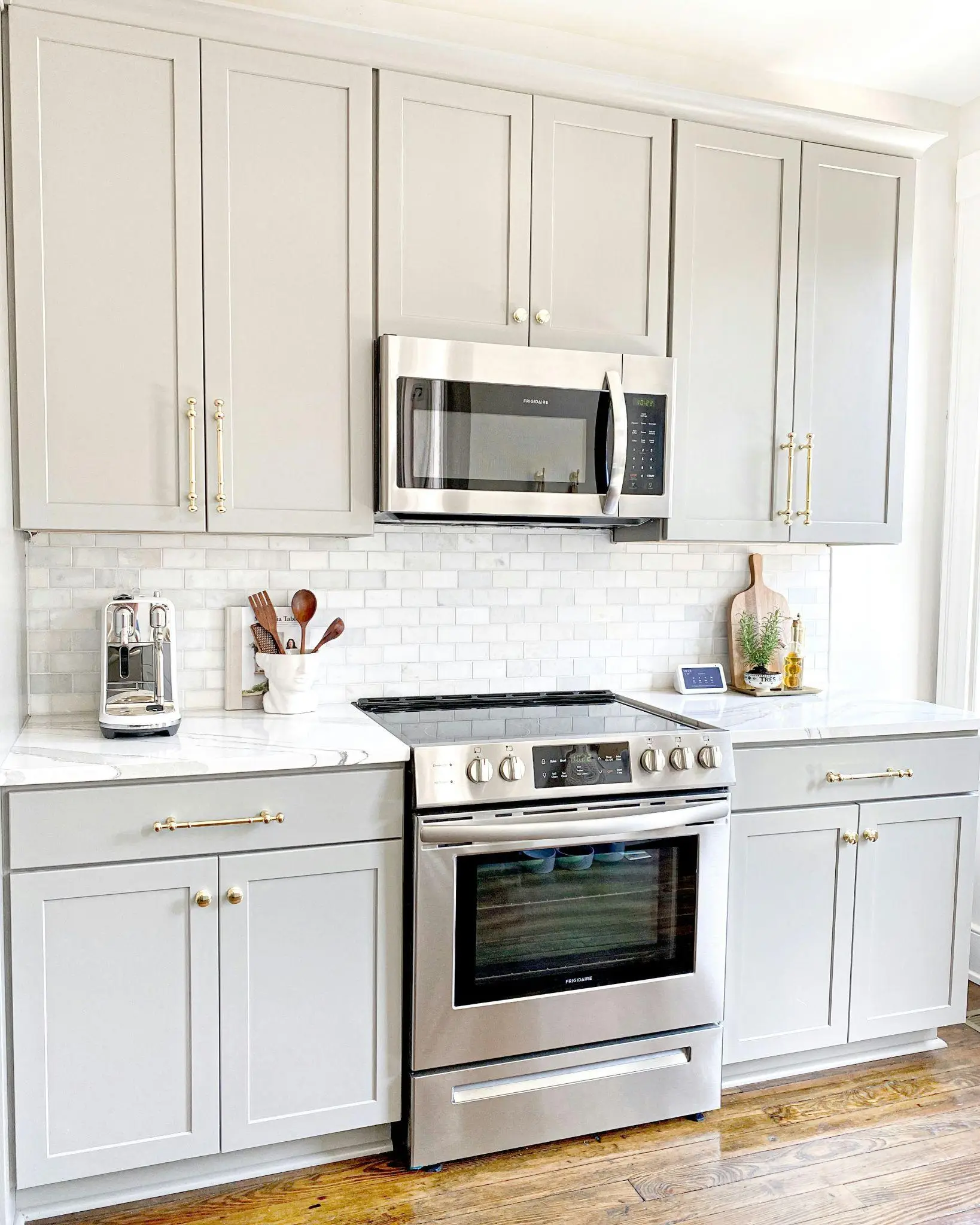 Modern kitchen with stainless steel oven, white cabinets, and marble countertop under natural light