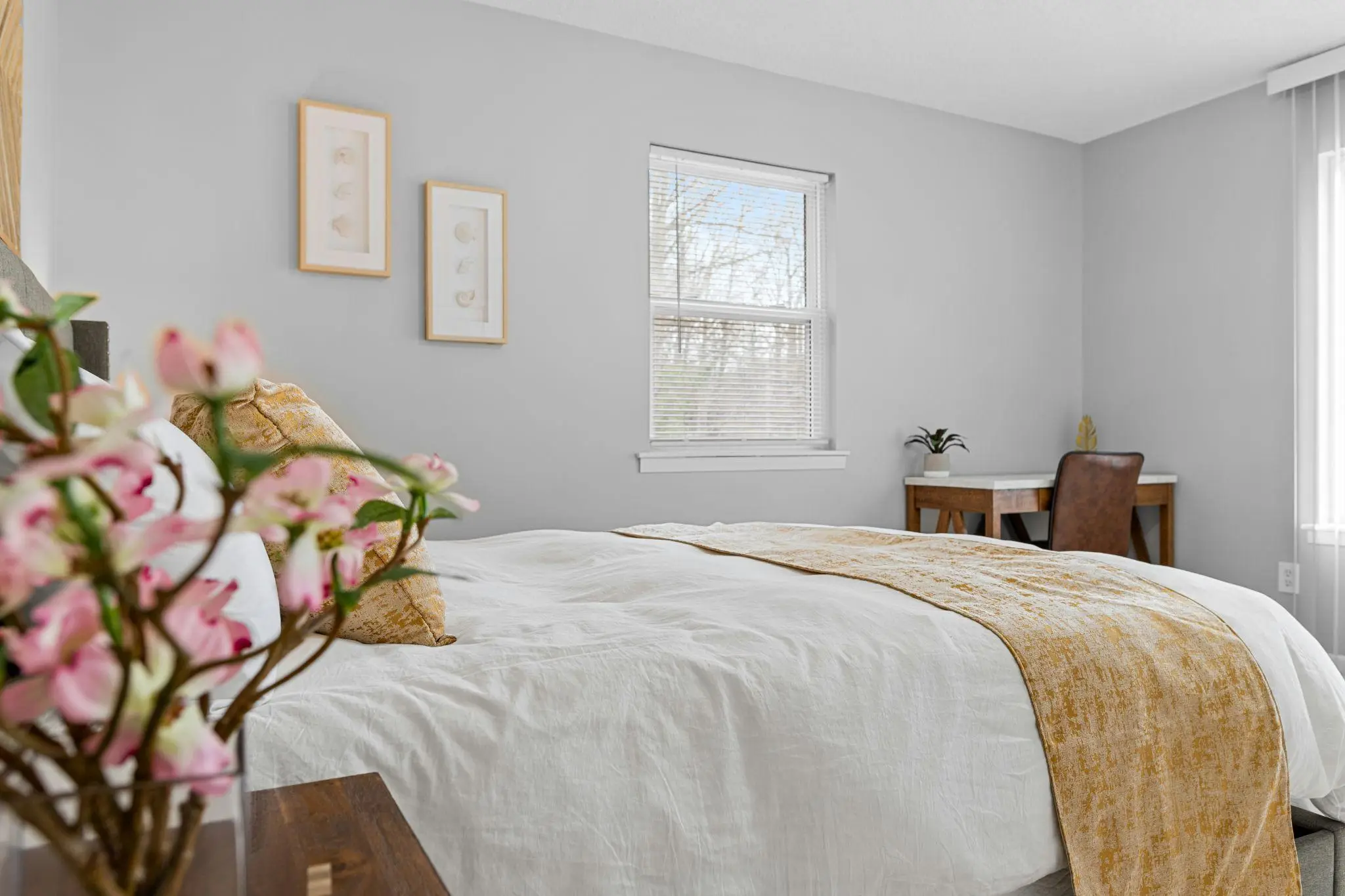 Cozy bedroom with white bedding and floral accents in bright natural light