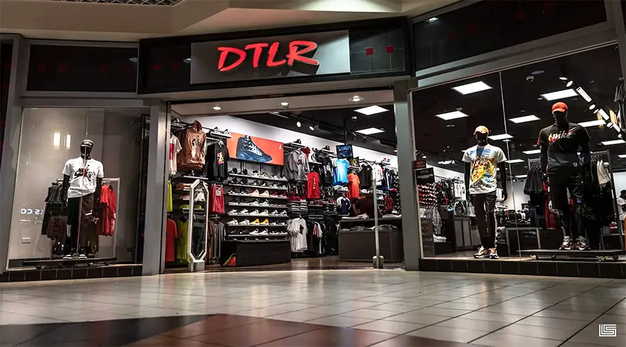 Clothing store exterior with mannequins displaying casual outfits and shelves filled with apparel and shoes