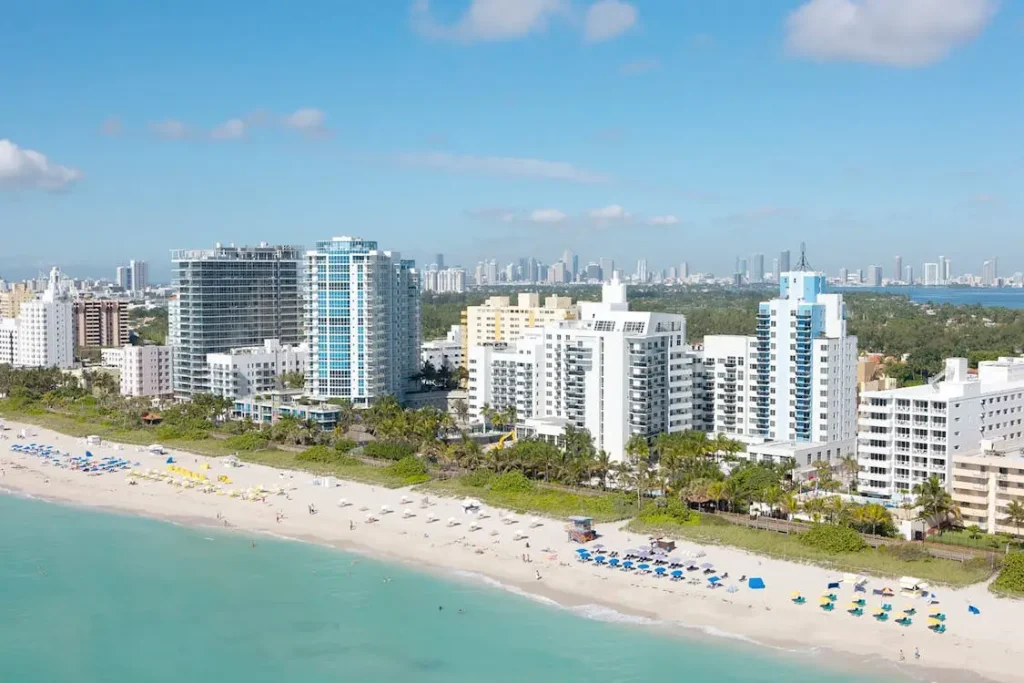 High-rise buildings overlooking sandy beach with colorful umbrellas and clear blue water