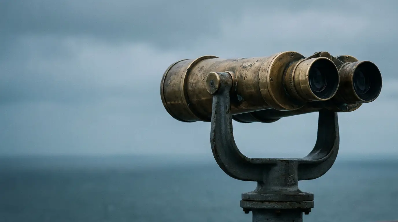 Brass telescope overlooking ocean under cloudy sky in coastal setting