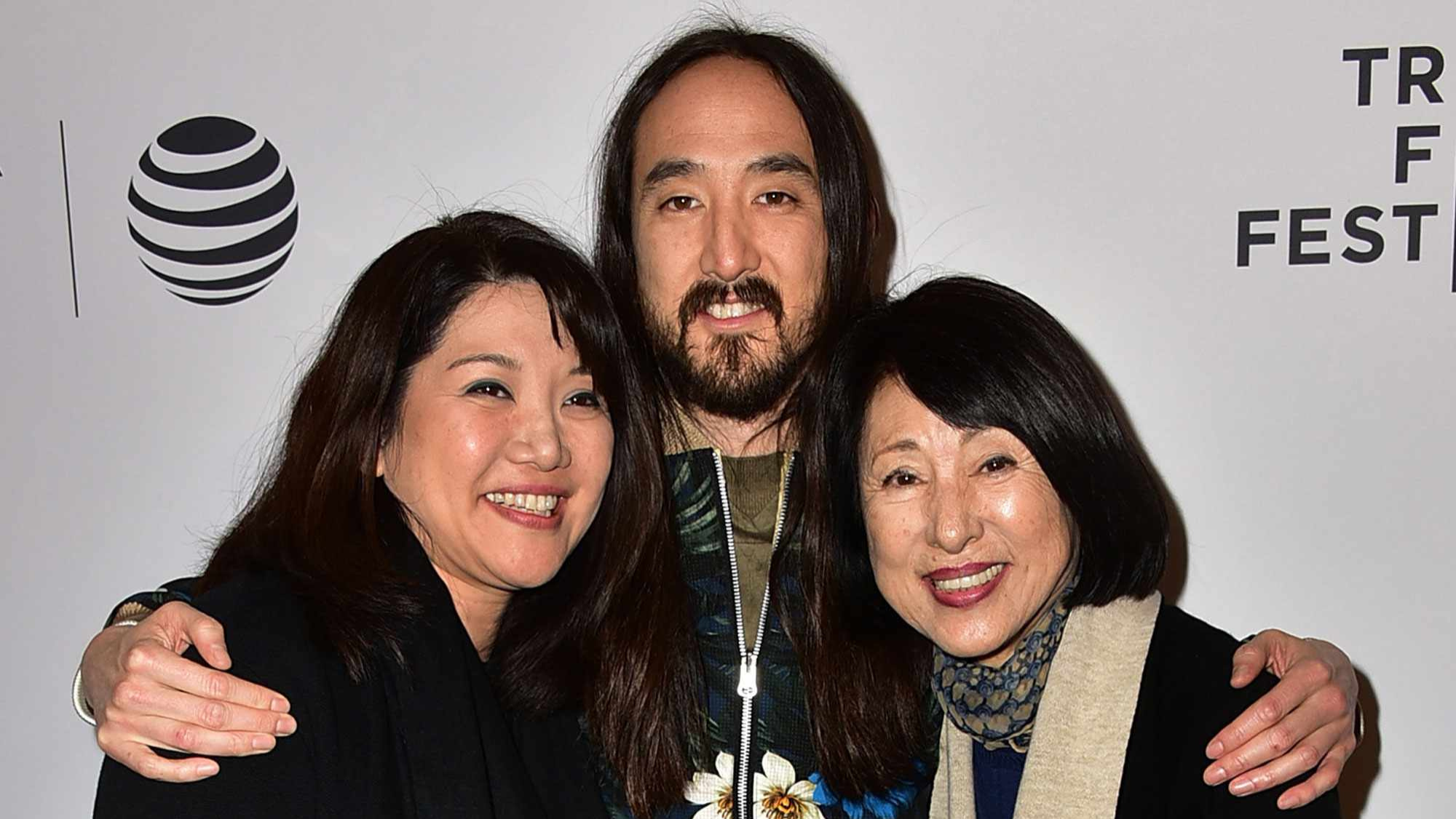 Steve Aoki posing with family members at a public event while smiling in front of a media backdrop.