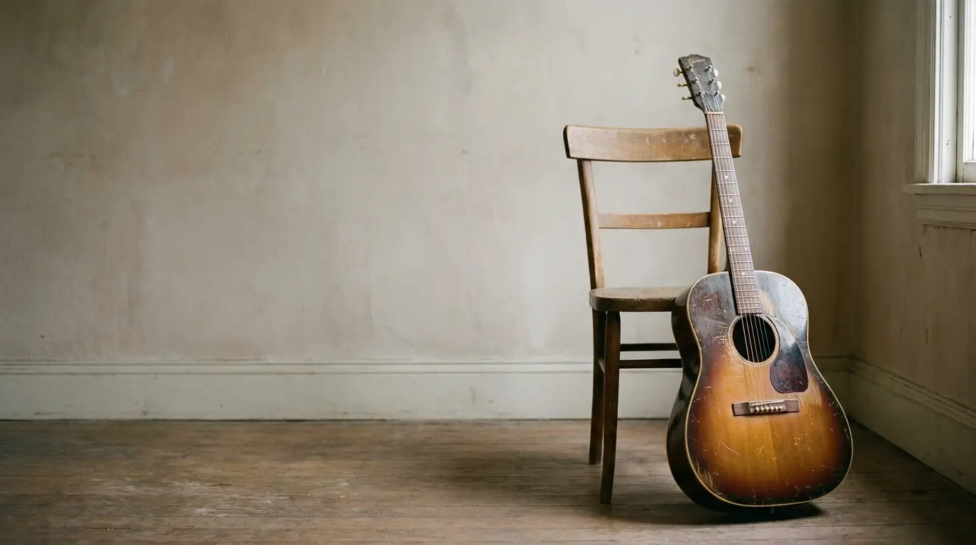 Vintage acoustic guitar leaning against wooden chair in rustic room with hardwood floor