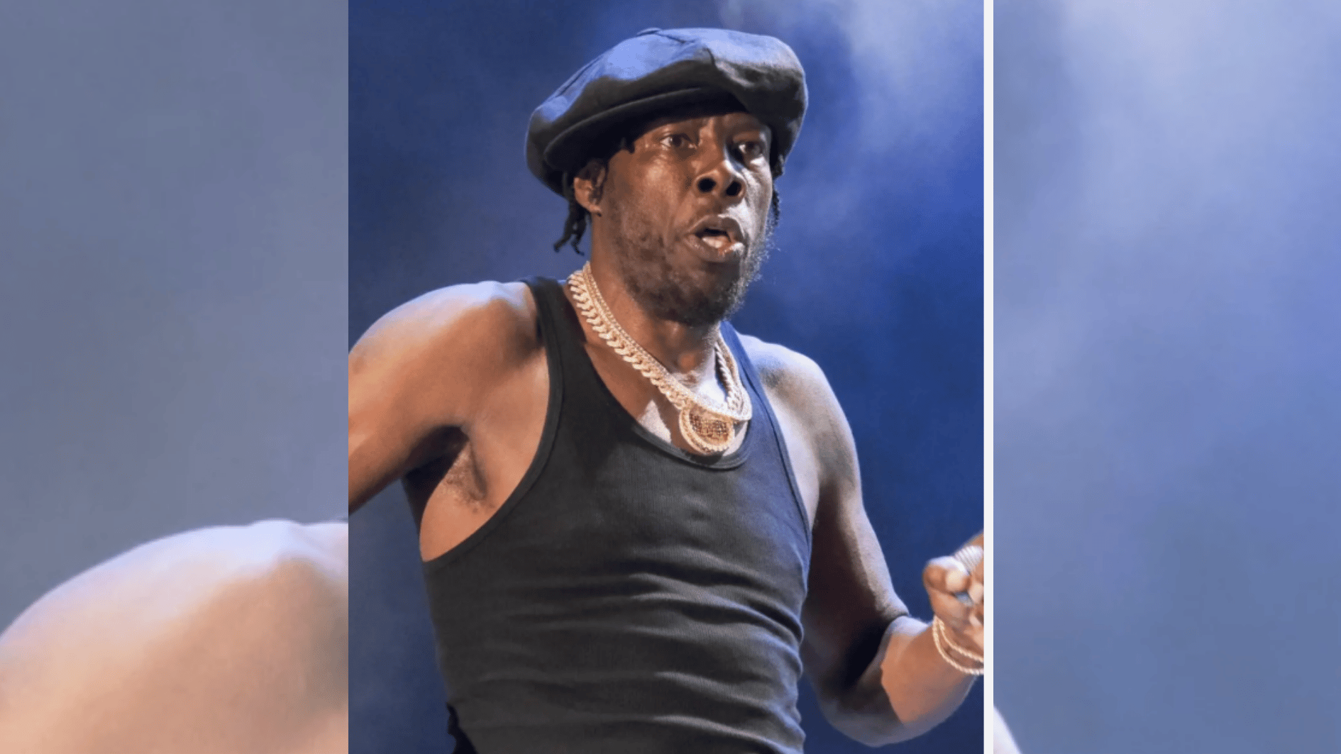 performer in black tank top and flat cap singing onstage under blue concert lighting.