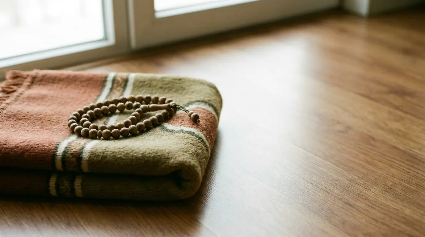 Folded blanket with wooden beads on wooden floor near window