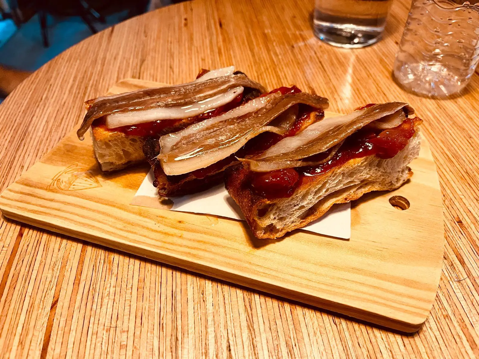 Bruschetta with anchovies on wooden board in cozy indoor setting