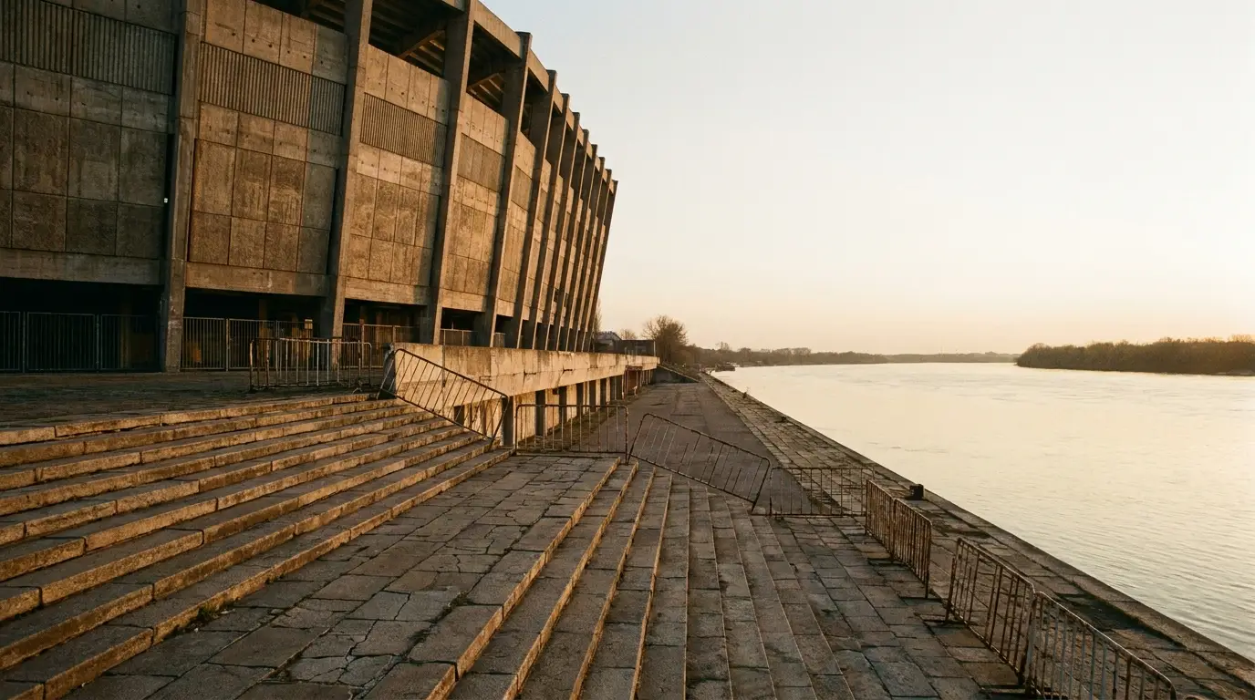 Brutalist concrete building with stairs beside a calm river at sunset