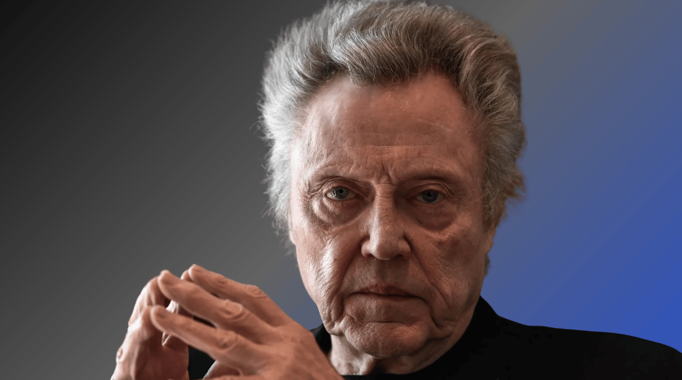 Christopher Walken, who plays Emperor Shaddam IV in Dune, photographed in a close-up portrait wearing a black turtleneck against a gray and blue background.