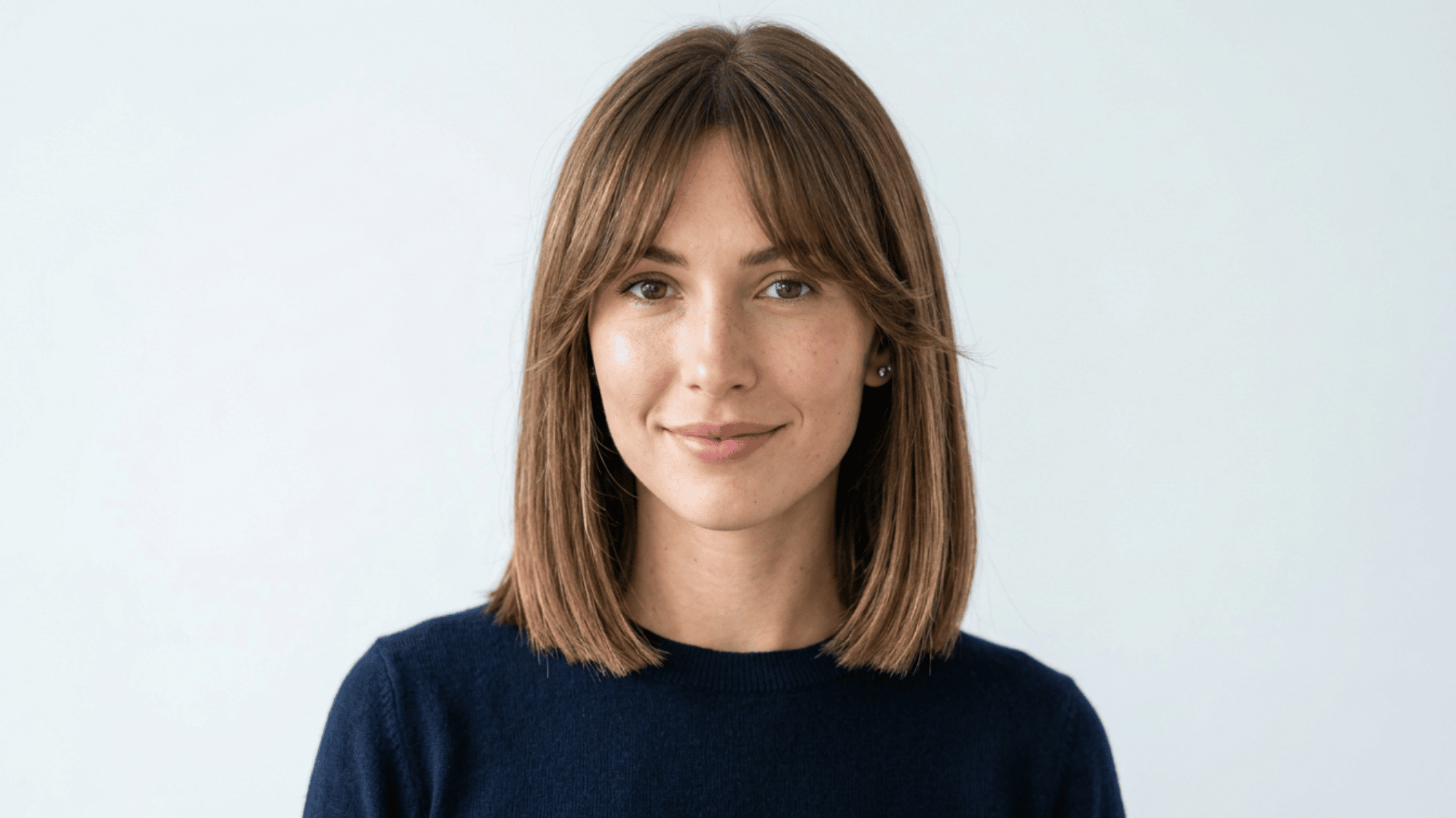 Woman with oblong face showing blunt bob with curtain bangs on white background