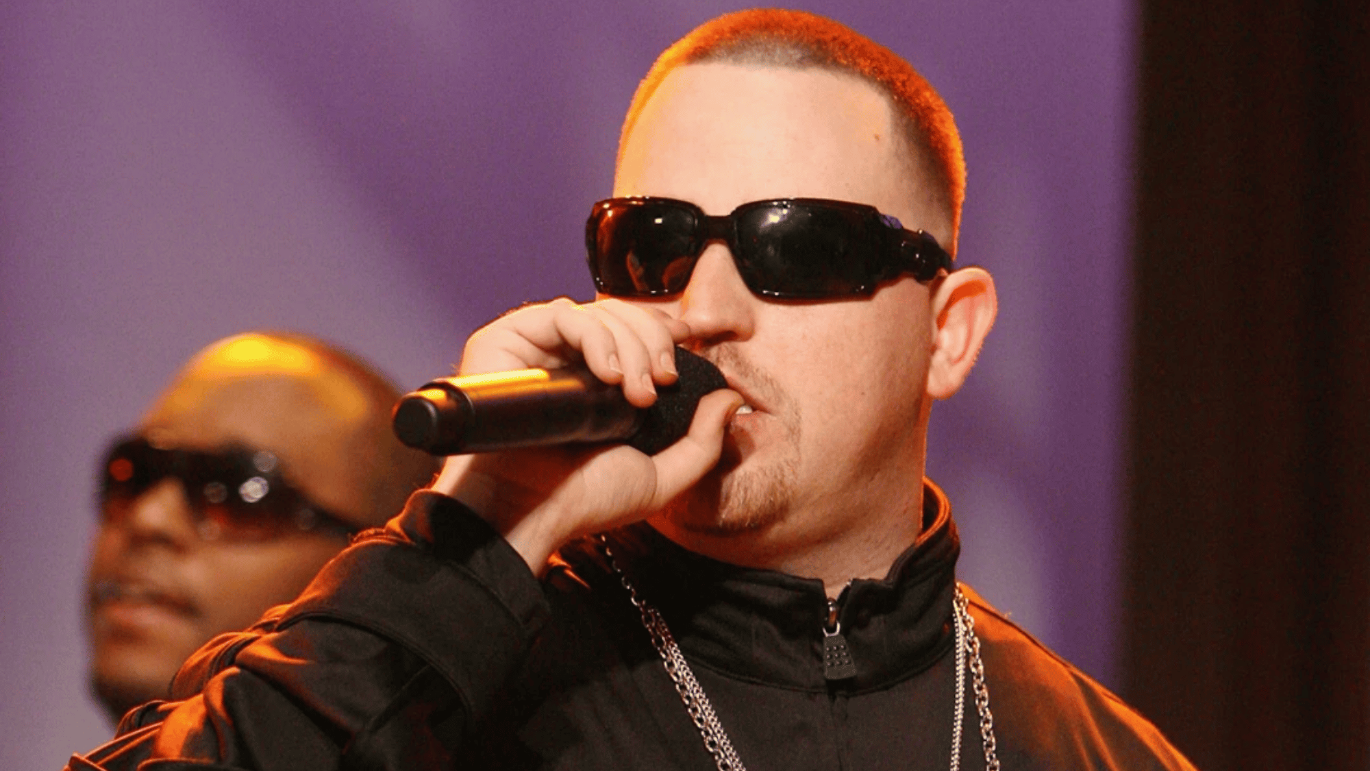 moonshine bandits member performing live on stage wearing black sunglasses and holding a microphone