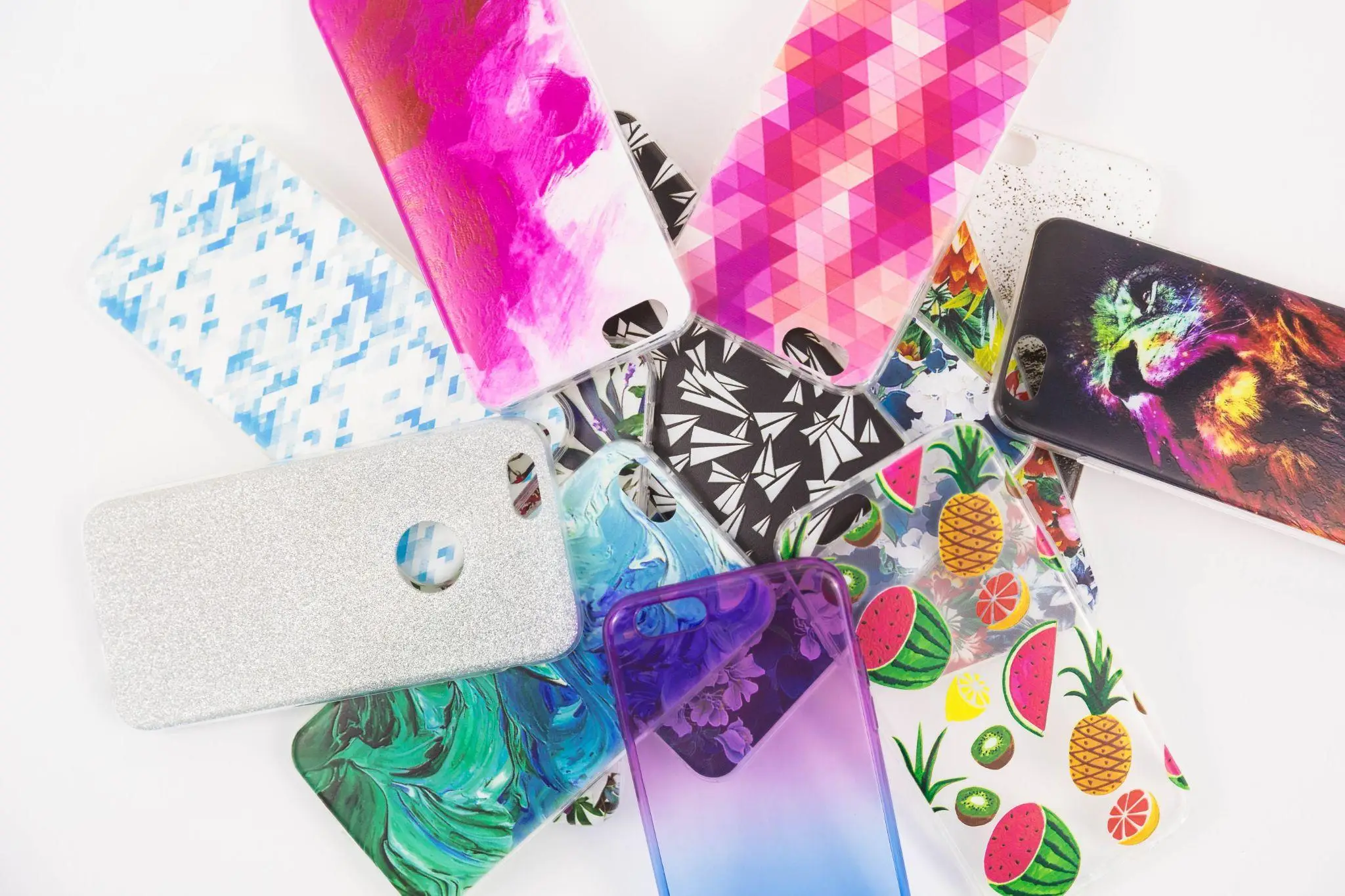 Assortment of colorful phone cases with geometric, animal, and fruit designs on white background