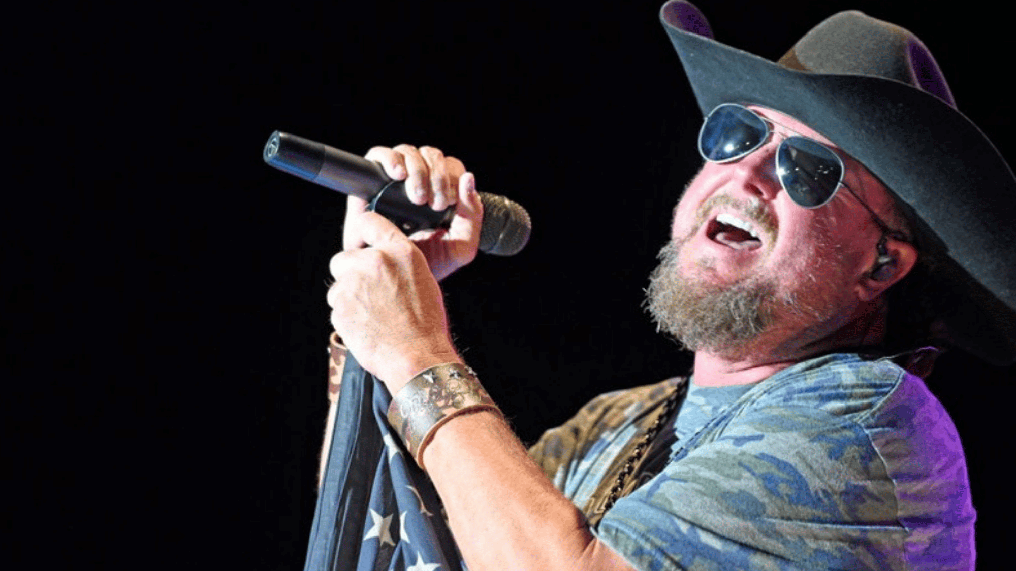 colt ford singing on stage wearing sunglasses and a cowboy hat while holding a microphone during concert