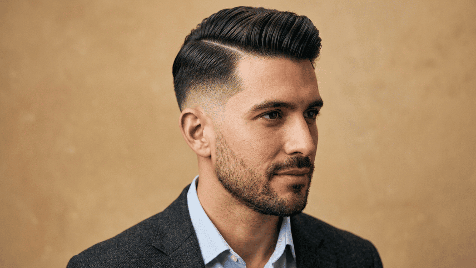 Man with oblong face showing polished comb over fade with sharp part and beard
