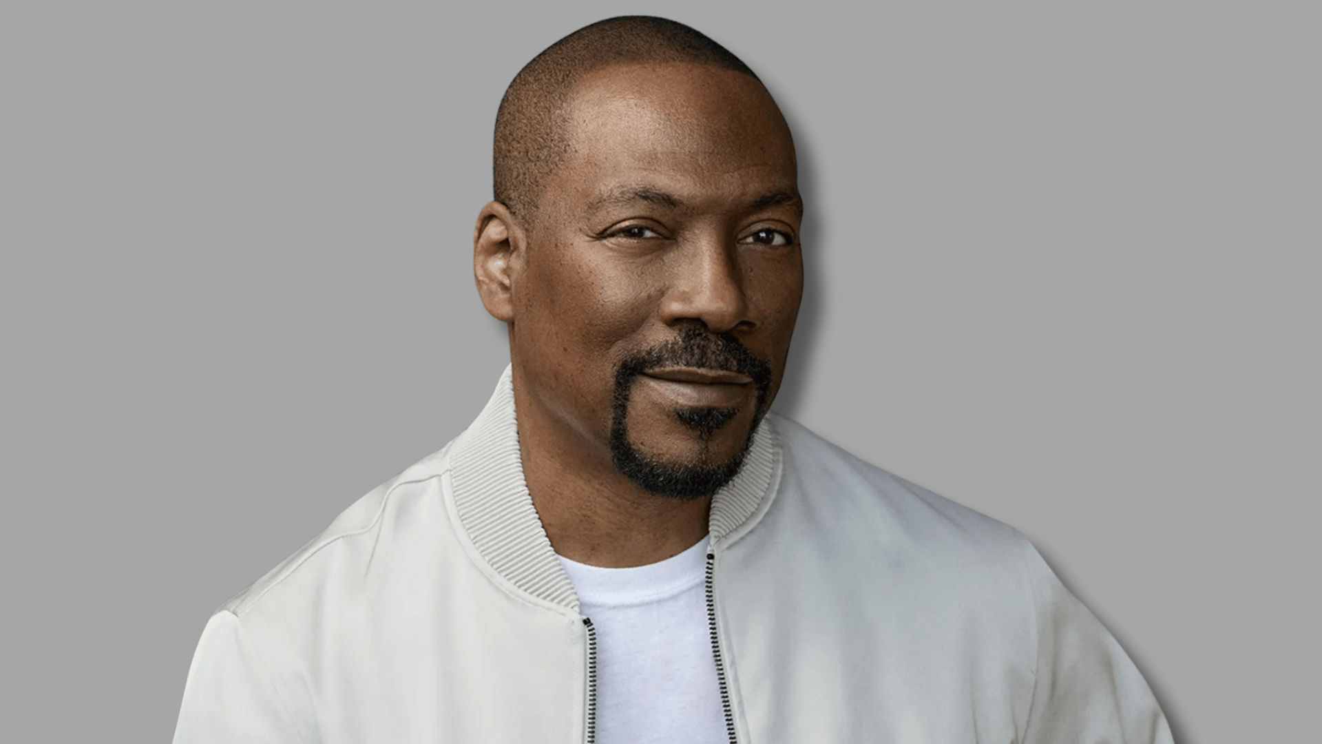 eddie murphy smiling in a light jacket during a professional portrait session