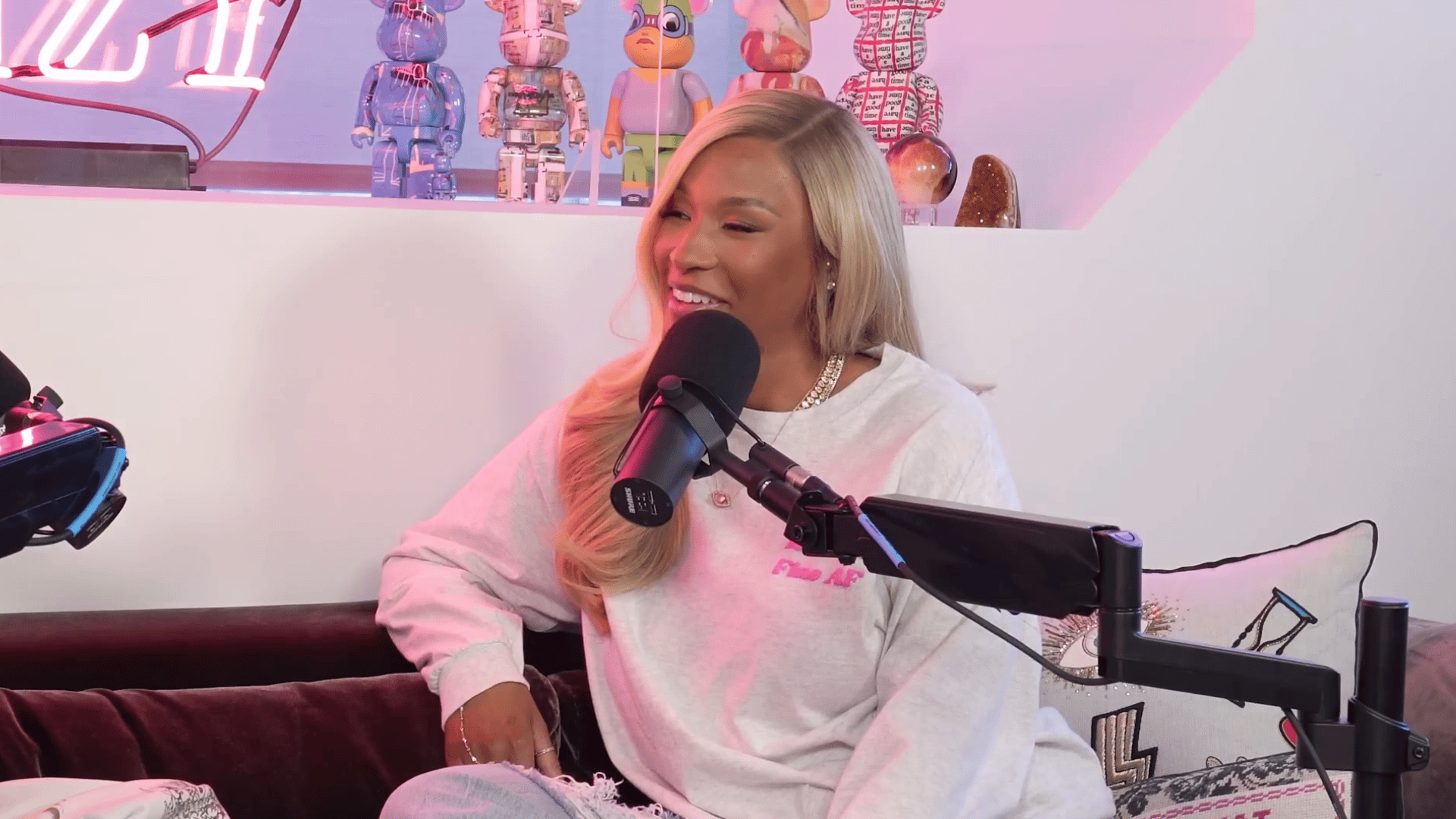 Savannah in white sweatshirt speaking into microphone on podcast set