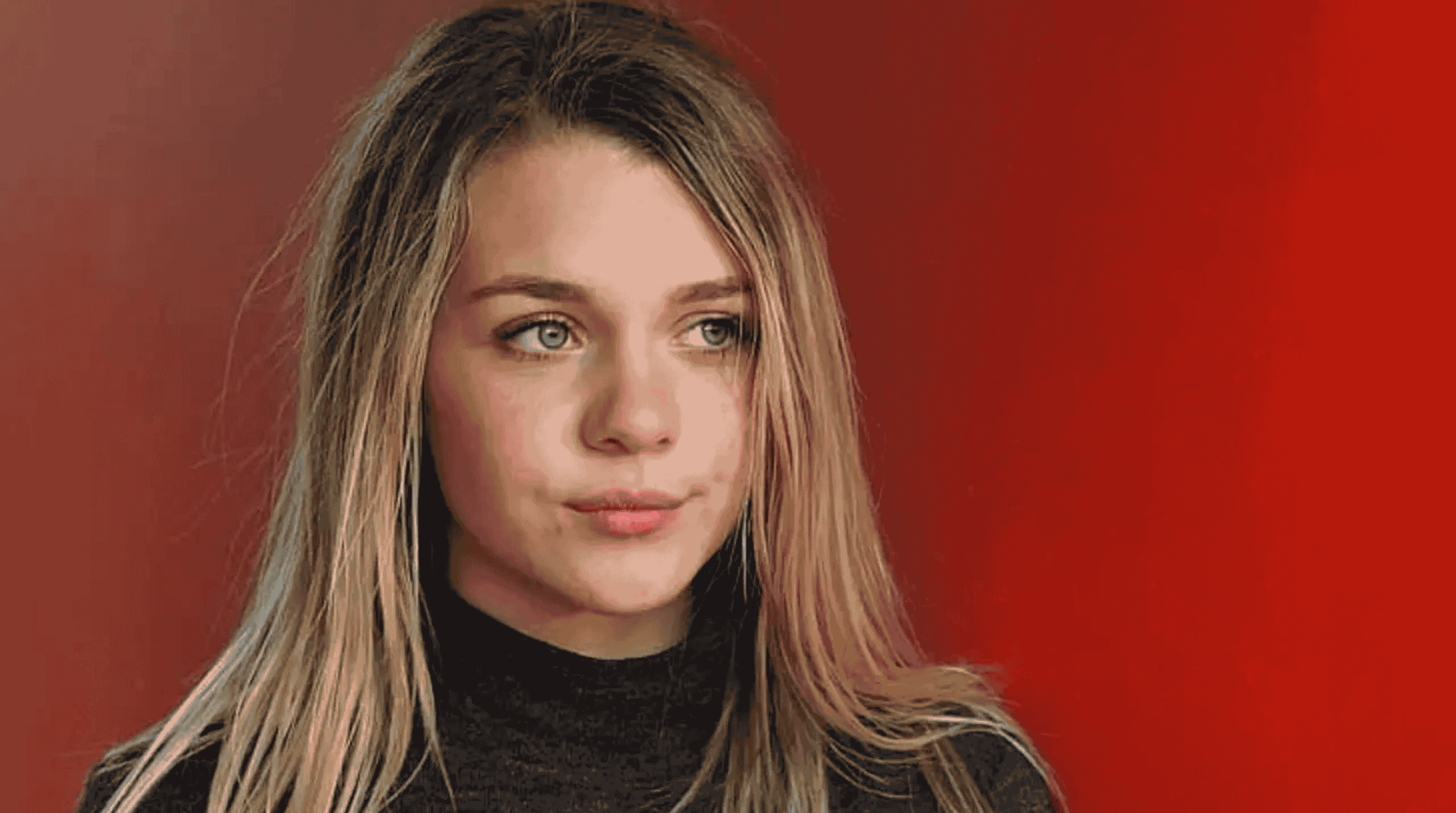 Gabbie Carter in a close-up portrait with long light brown hair, wearing a black top, looking thoughtful against a solid red background.