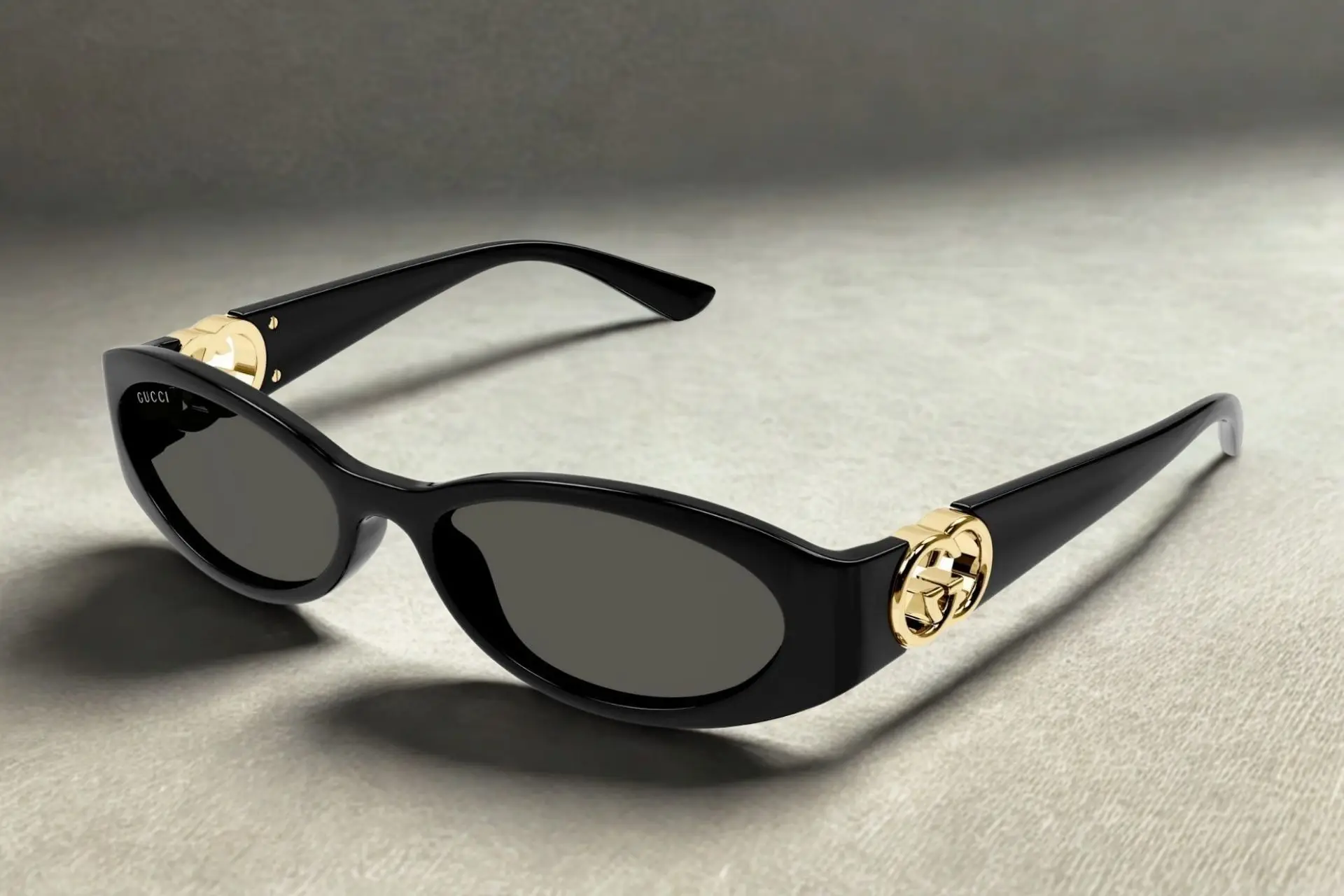 Black sunglasses with gold accents on neutral fabric background