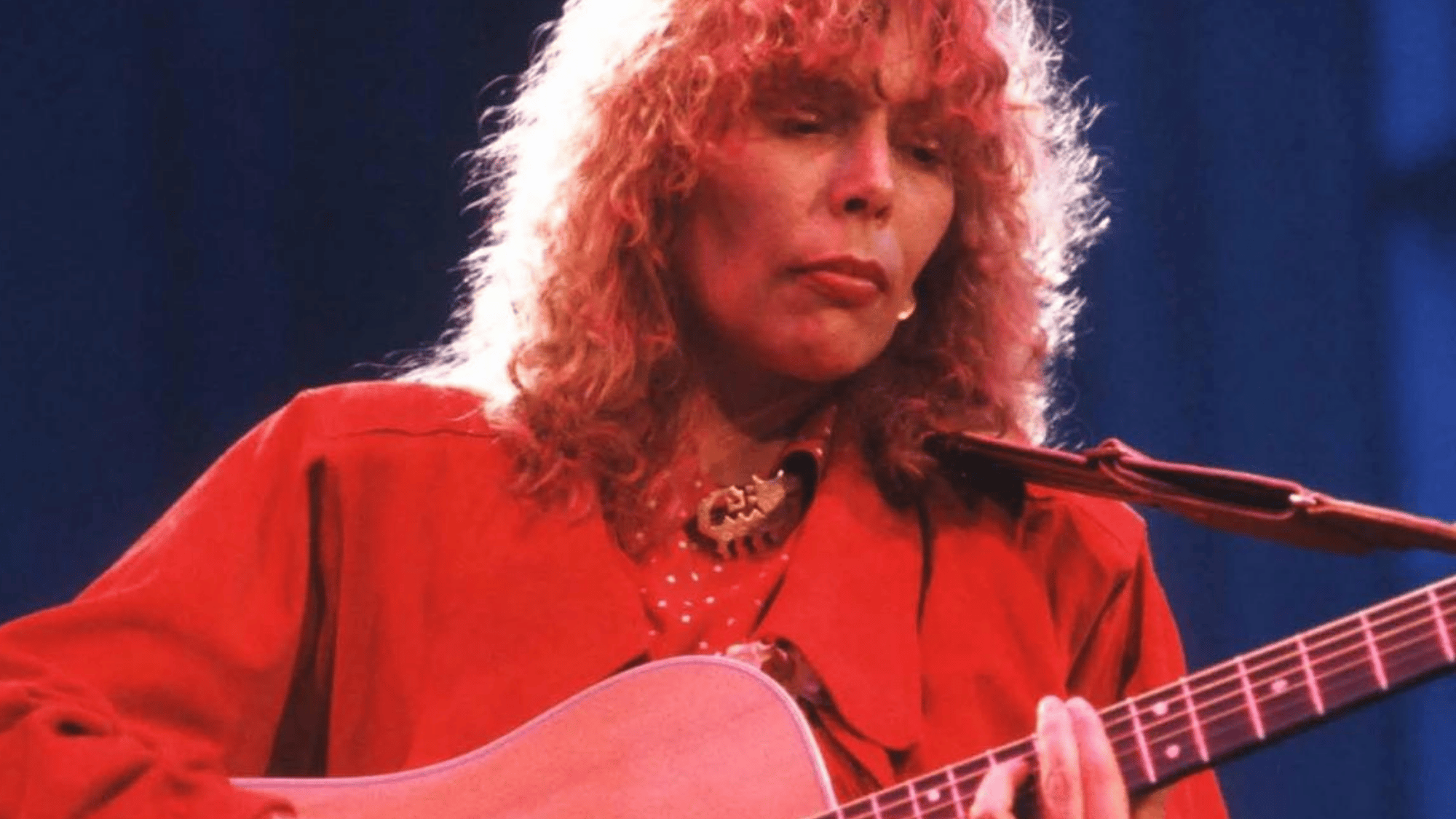 Joni Mitchell in her 40s live concert performance playing acoustic guitar