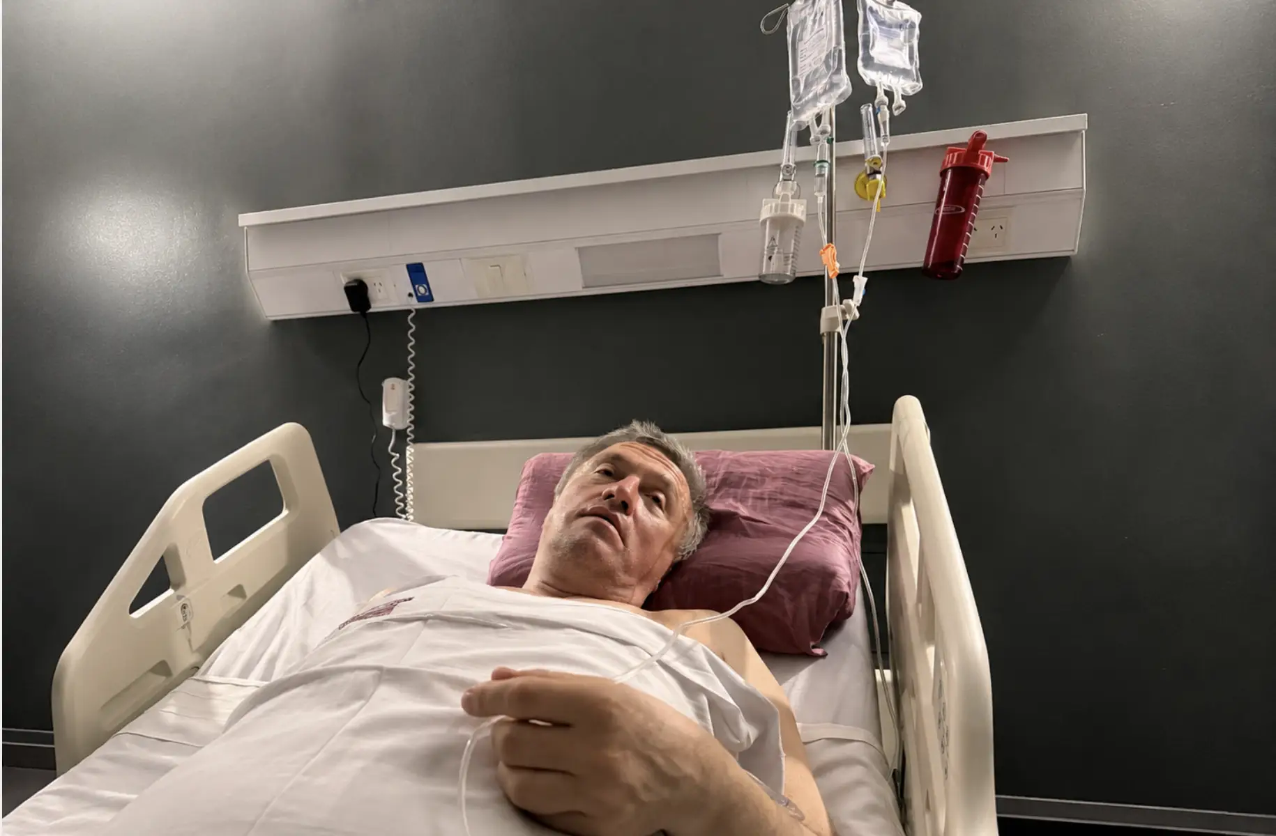 Patient lying in hospital bed with IV drip in clinical setting