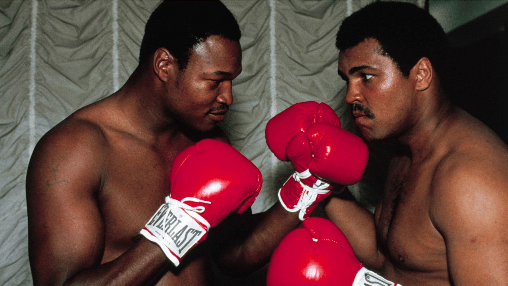 Larry Holmes and another boxer facing off, wearing red gloves, preparing for a fight.