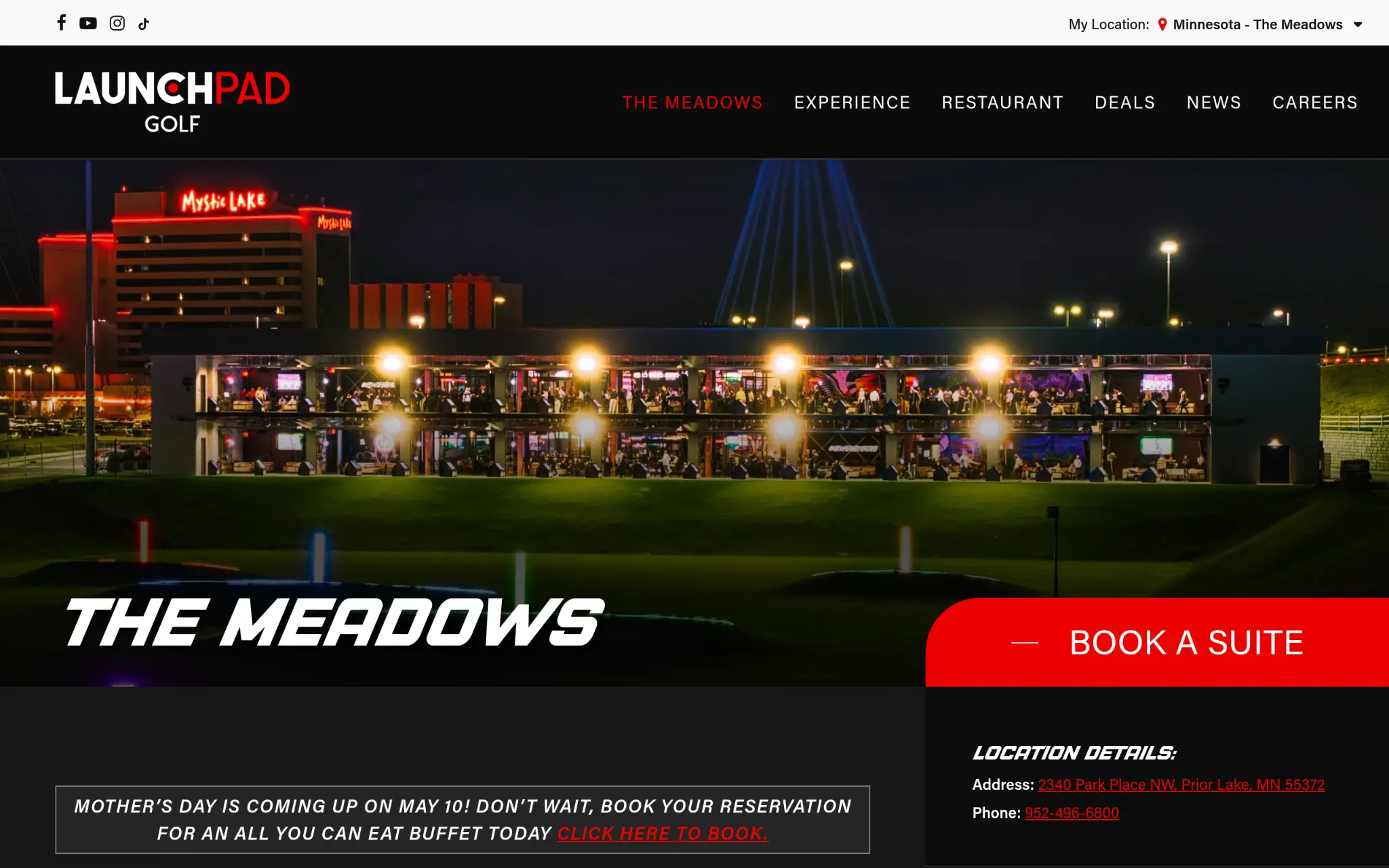 Outdoor golf driving range with illuminated bays at night, building in the background.