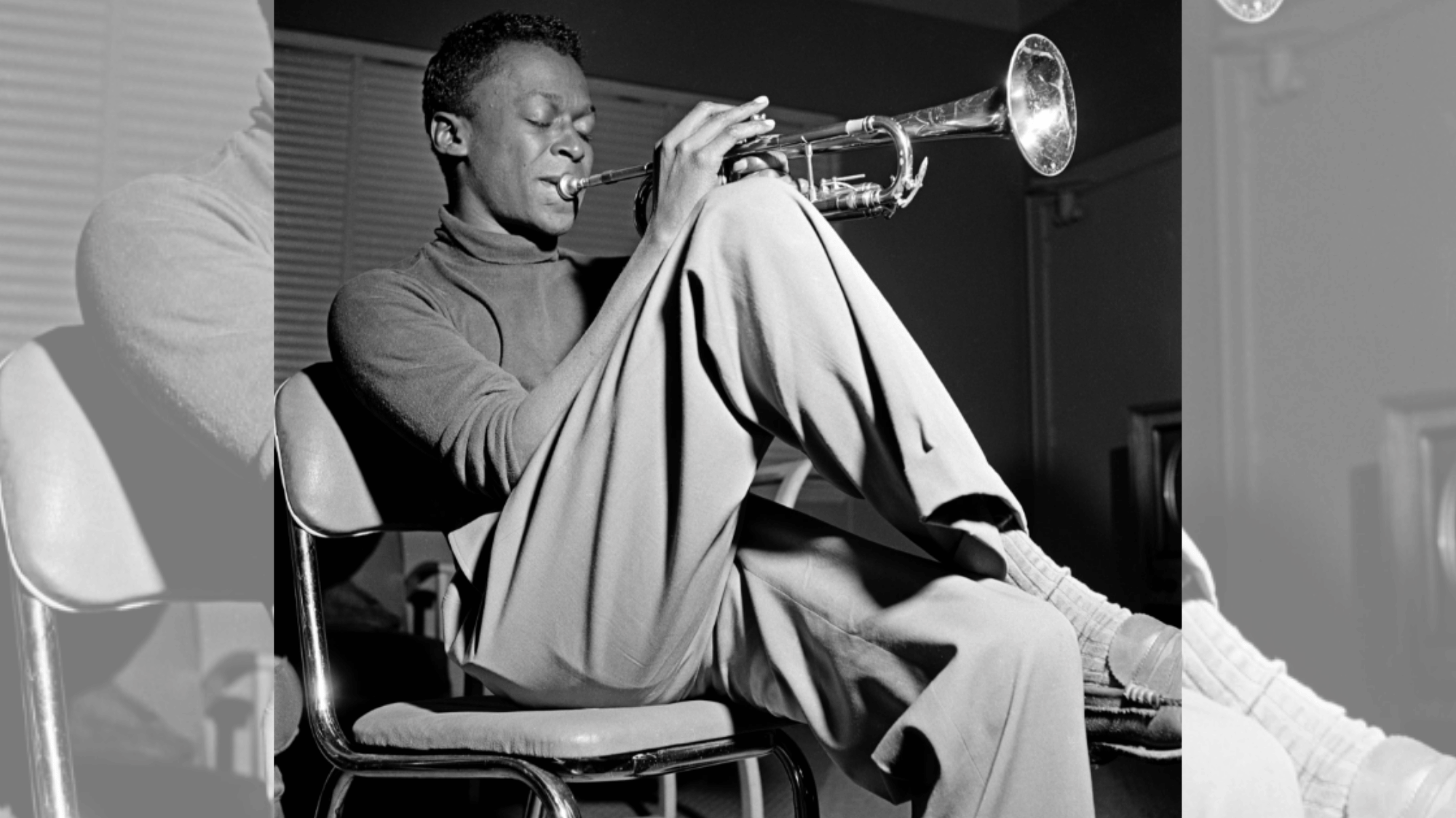 miles davis seated while playing trumpet during an intimate black and white jazz session