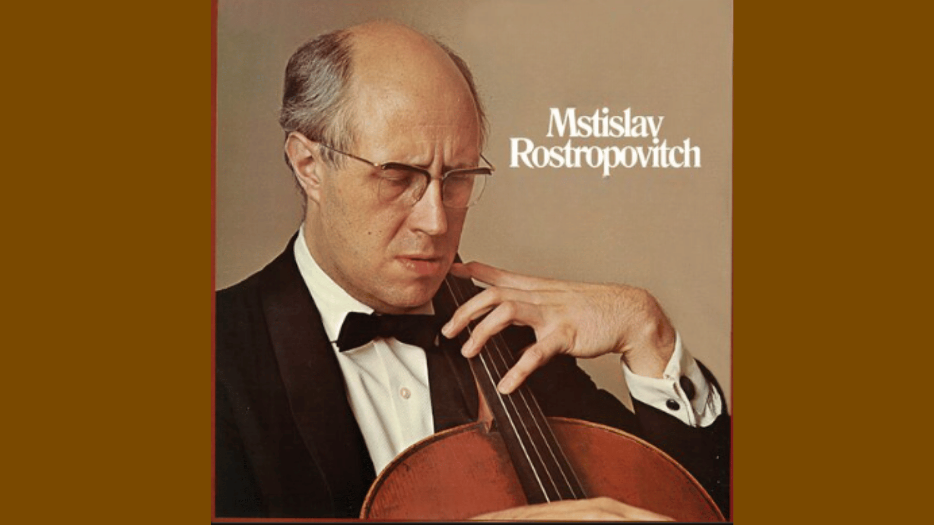 Mstislav Rostropovich performing cello during a classical concert with orchestra and dramatic stage lighting.