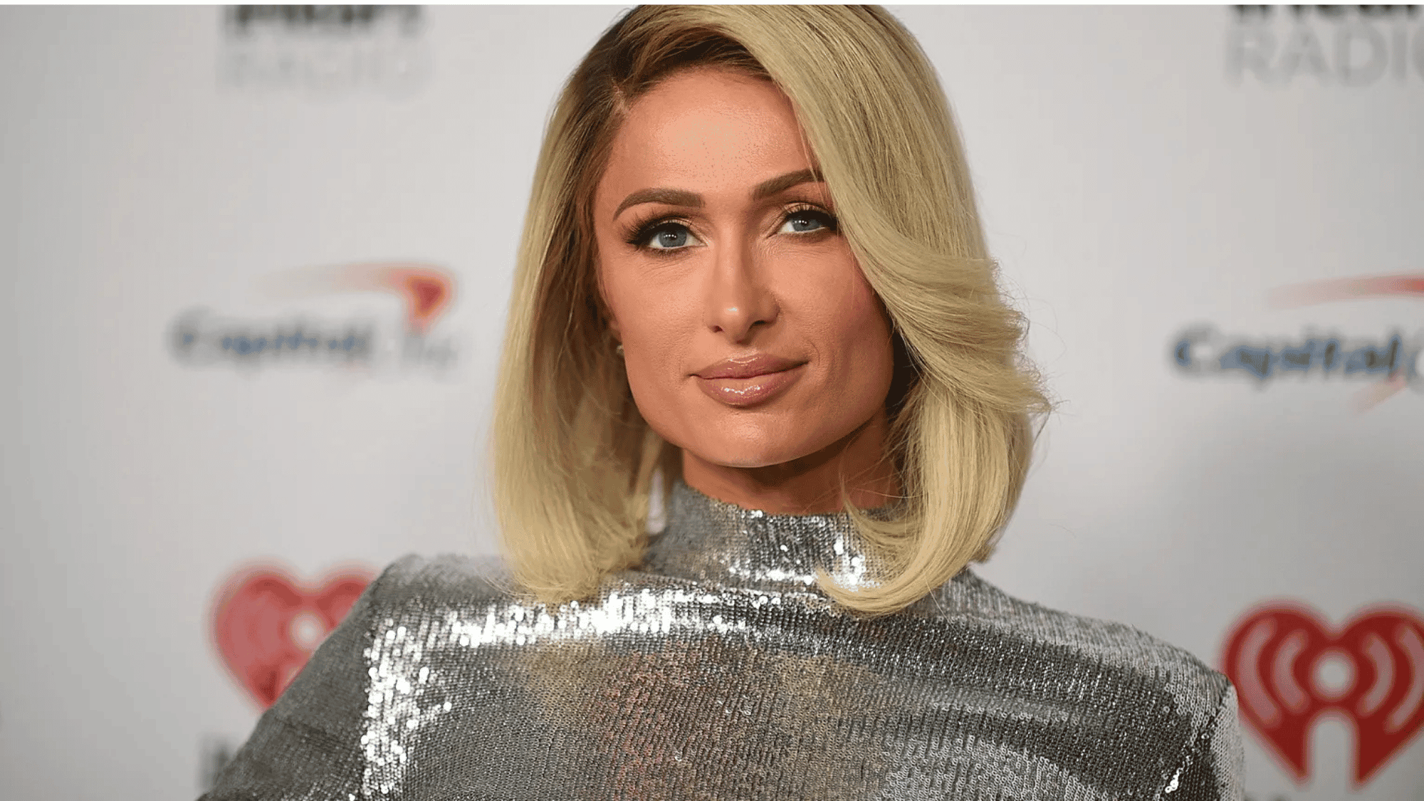 Paris Hilton smiling in a glamorous dress, symbolizing her media and business success