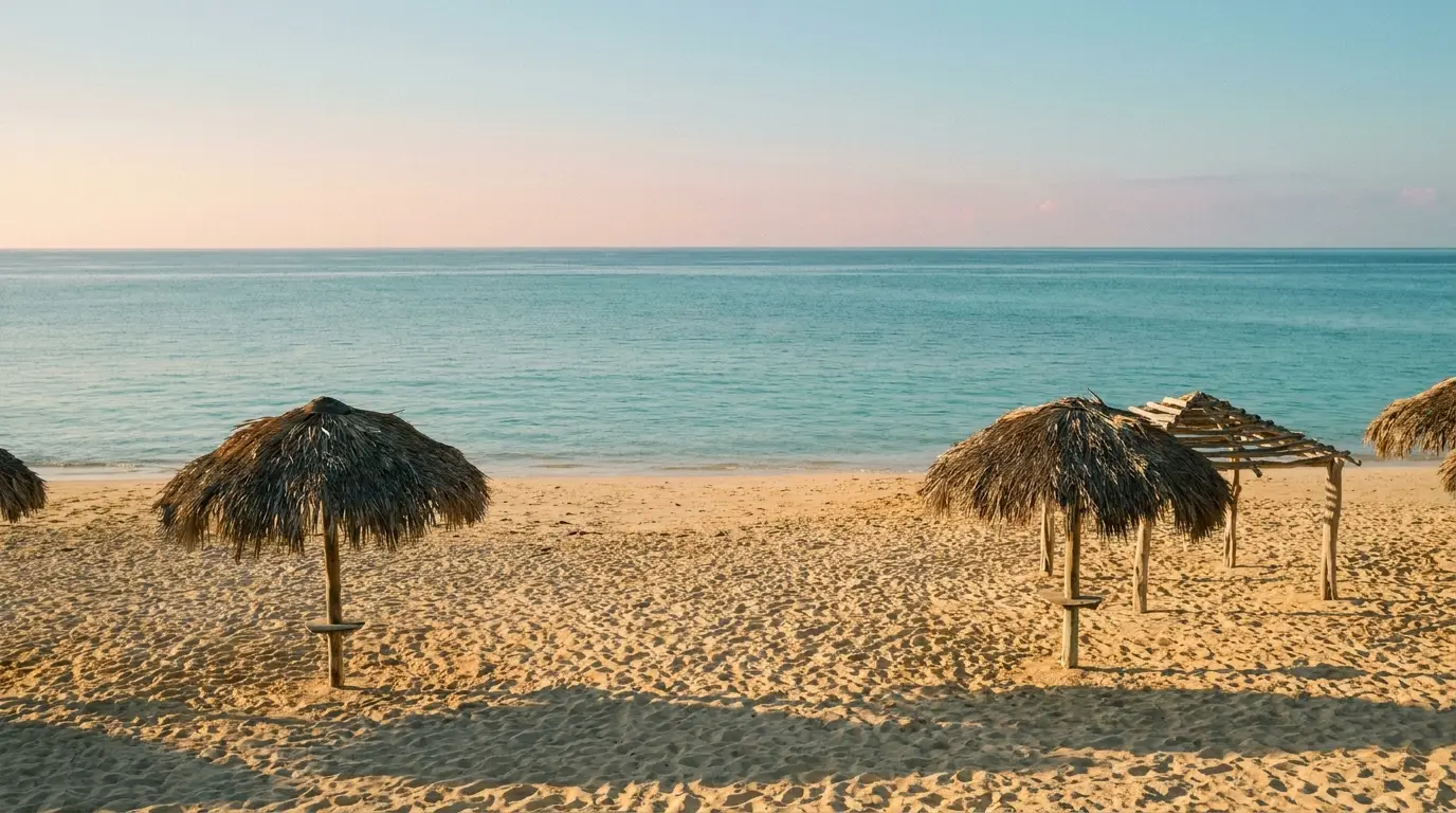 Tropical beach with thatched umbrellas on sand overlooking calm turquoise sea