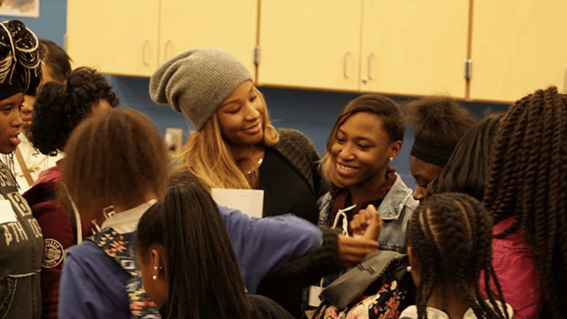 Savannah in grey beanie smiling and engaging with a group of young girls at a community event