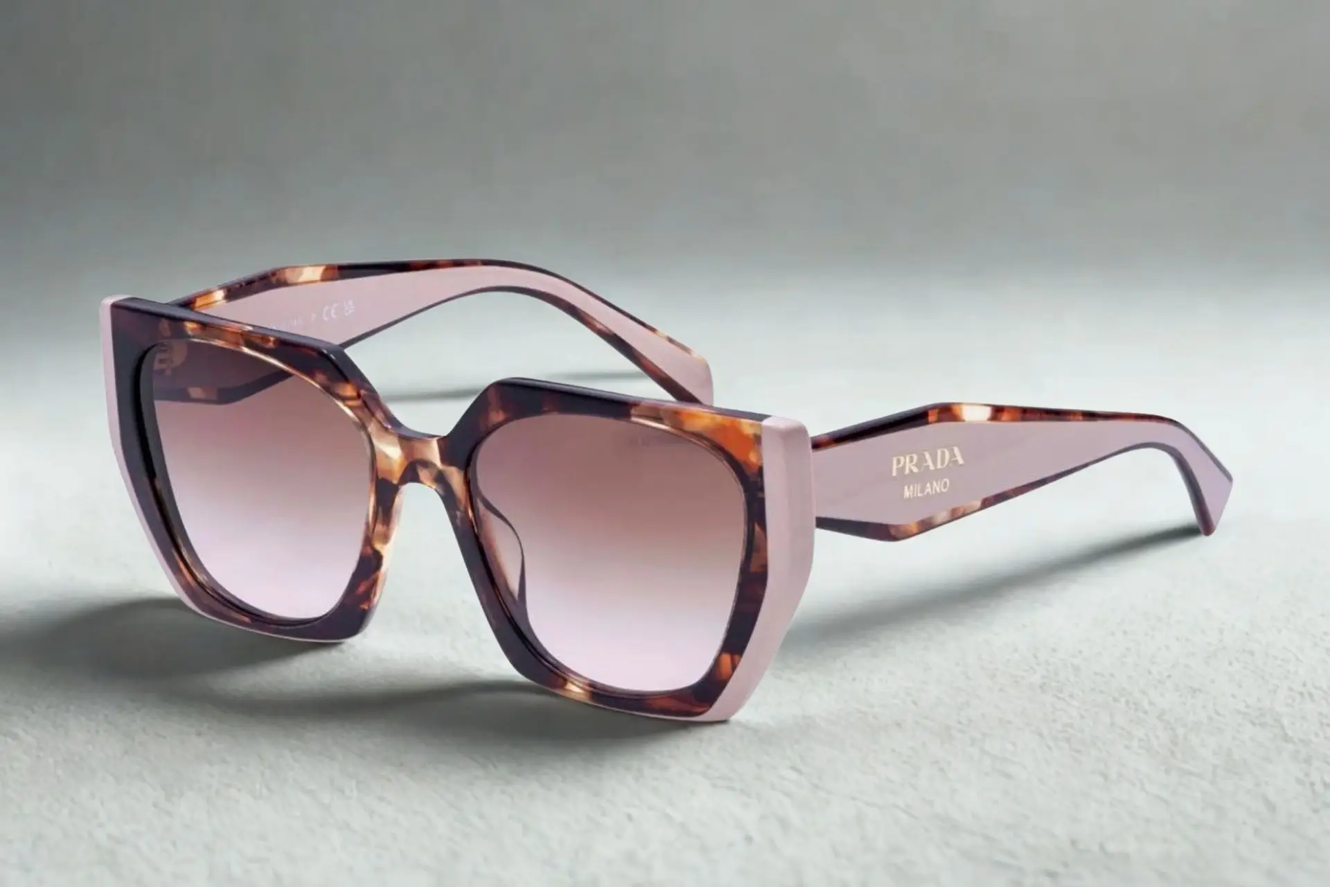 Tortoiseshell oversized sunglasses with gradient lenses on textured surface