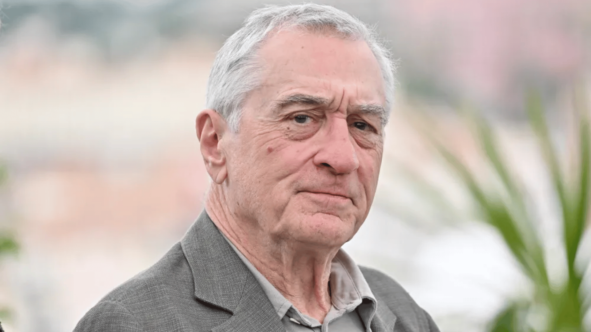 Robert De Niro wearing a gray suit while being photographed