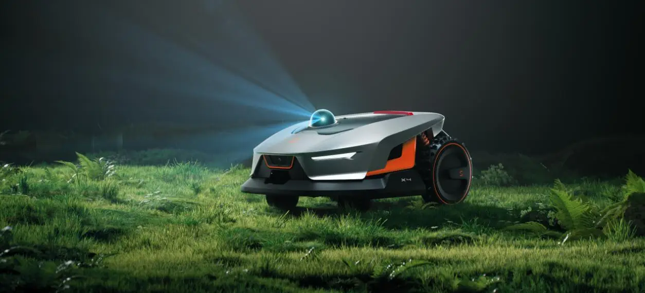 Futuristic robotic lawn mower with LED lights on grassy field under dim lighting