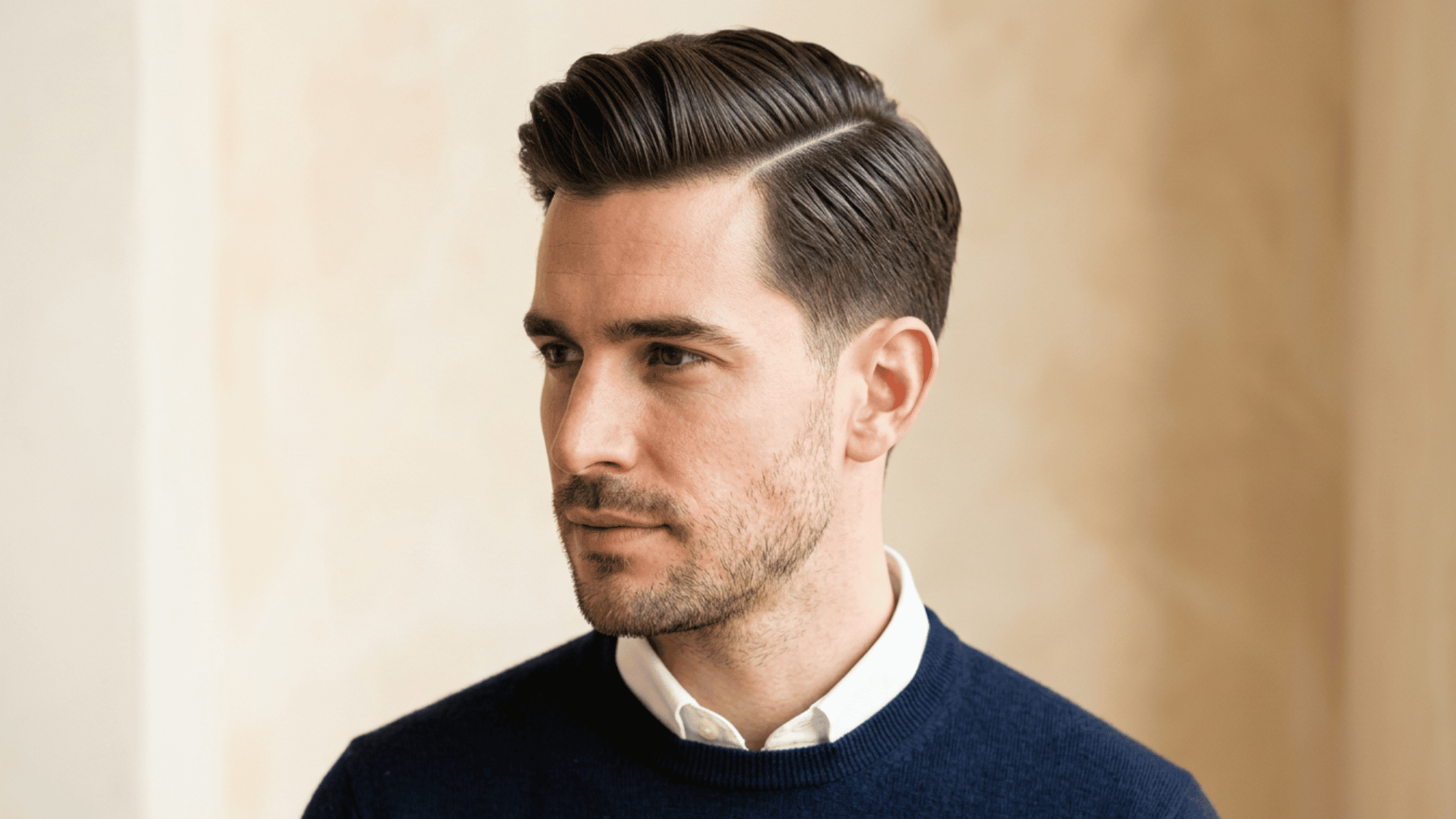 Man with oblong face showing polished side part with tapered fade on beige background