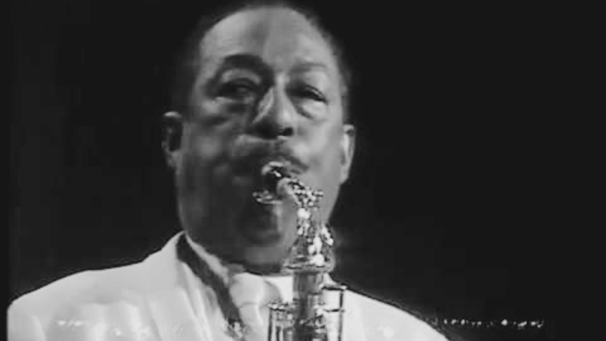 Here are 3 SEO-optimized alt text options for this image to be used for Sophisticated Lady: Option 1 — (105 characters): Duke Ellington orchestra saxophonist performing Sophisticated Lady close up black and white photo Option 2 — (112 characters): Jazz saxophonist from Duke Ellington orchestra performing Sophisticated Lady black and white live photo Option 3 — (108 characters): Duke Ellington Sophisticated Lady era saxophonist close up black and white archival performance photo
