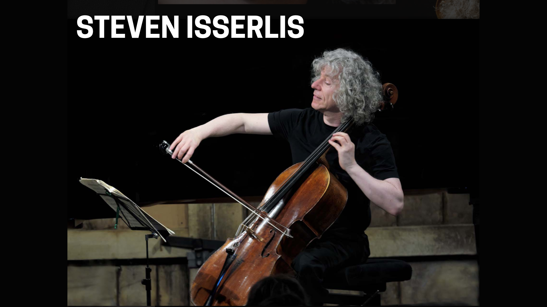 Steven Isserlis playing cello during a live classical music performance with warm concert hall lighting.