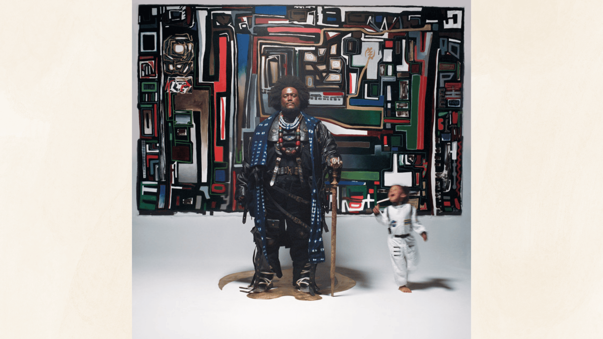 stylized portrait of musician standing before colorful abstract artwork beside playful child in white outfit