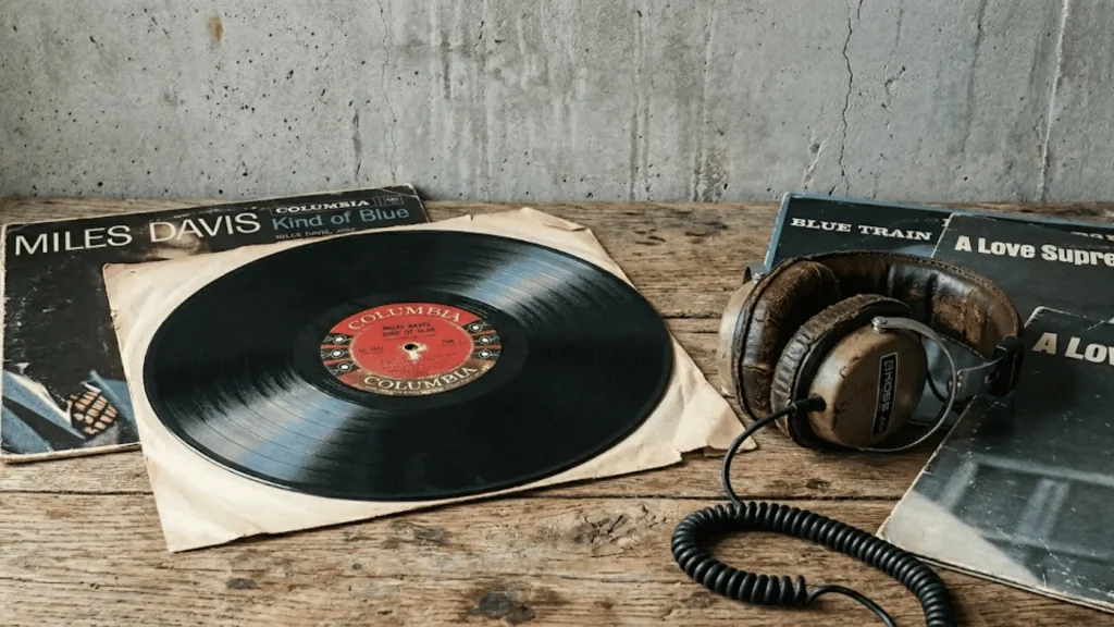 vintage vinyl record with album sleeves and worn headphones on a weathered wooden surface in natural light