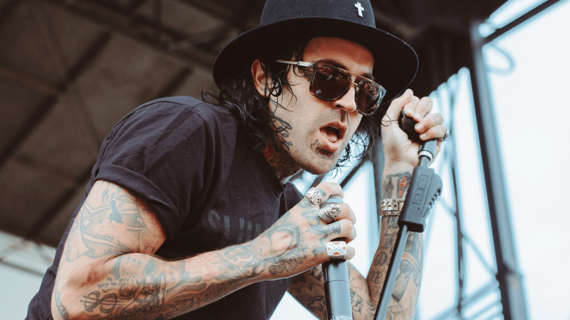 yelawolf performing live on stage wearing sunglasses and a black hat while singing into a microphone
