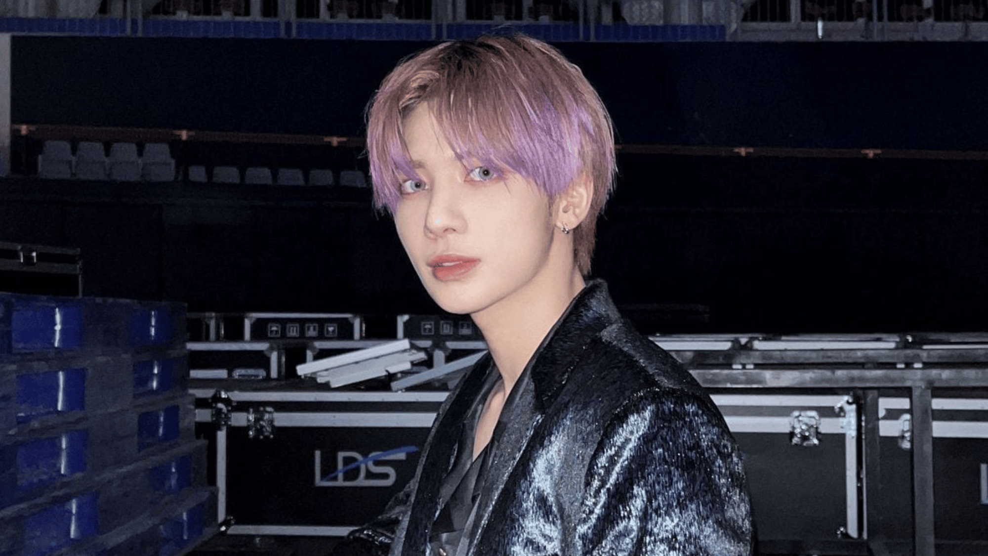 a man backstage wearing a black outfit and purple hair
